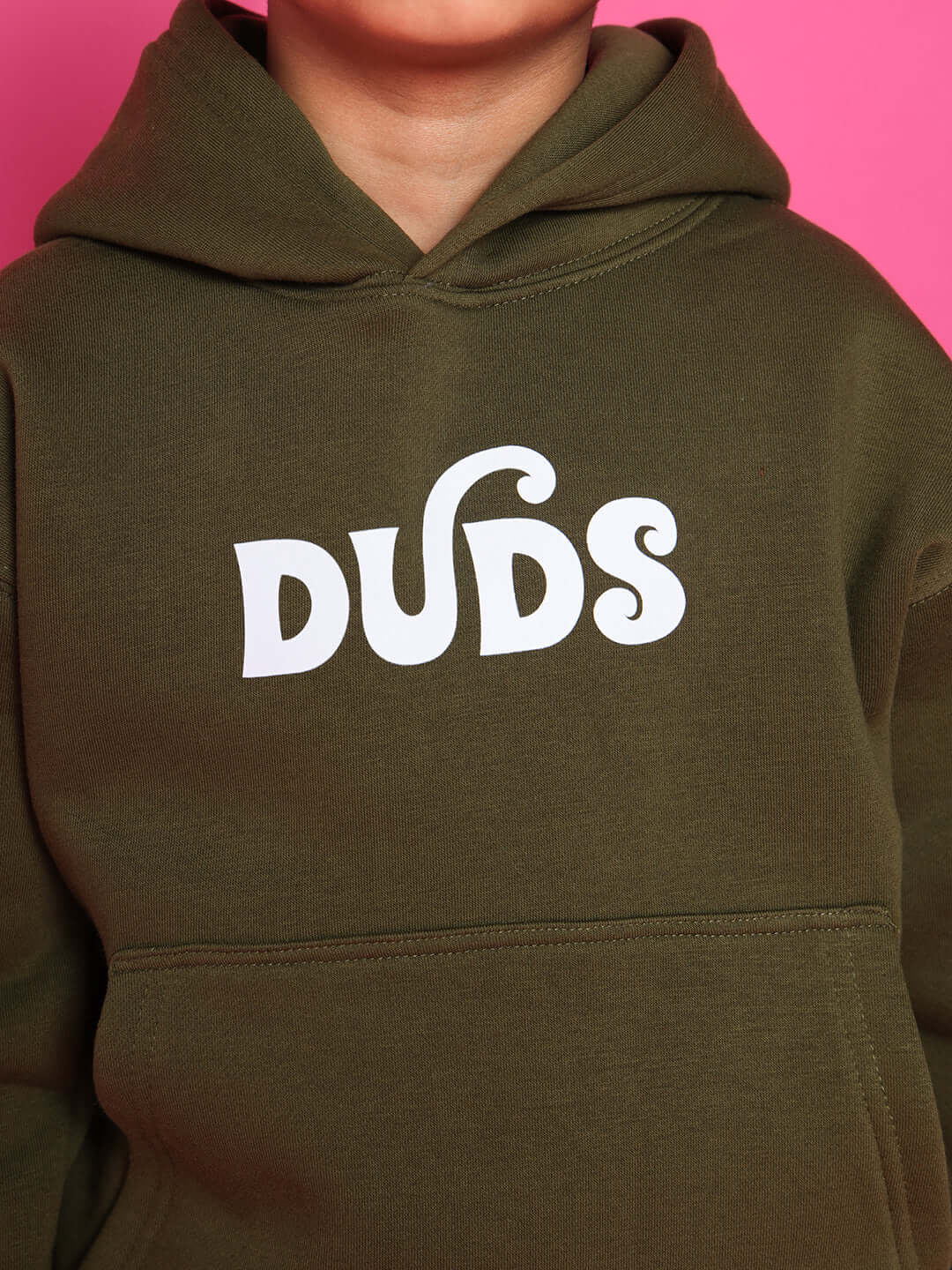 Olive green hoodie for kids with 'DUDS' print, set against a pink background