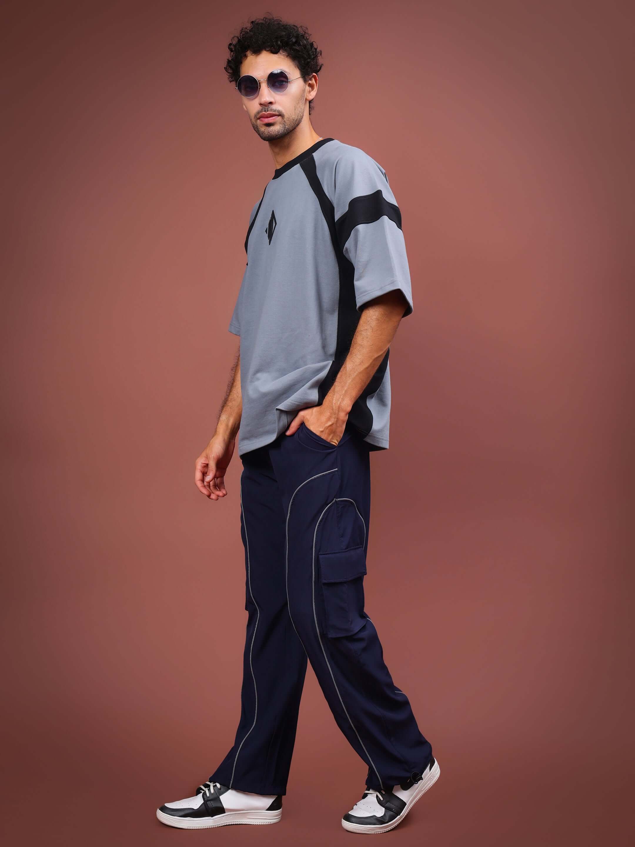 Model wearing RAY REFLECTOR PARACHUTE CARGO PANTS in navy blue, featuring custom fit option and cargo pockets, paired with stylish attire.
