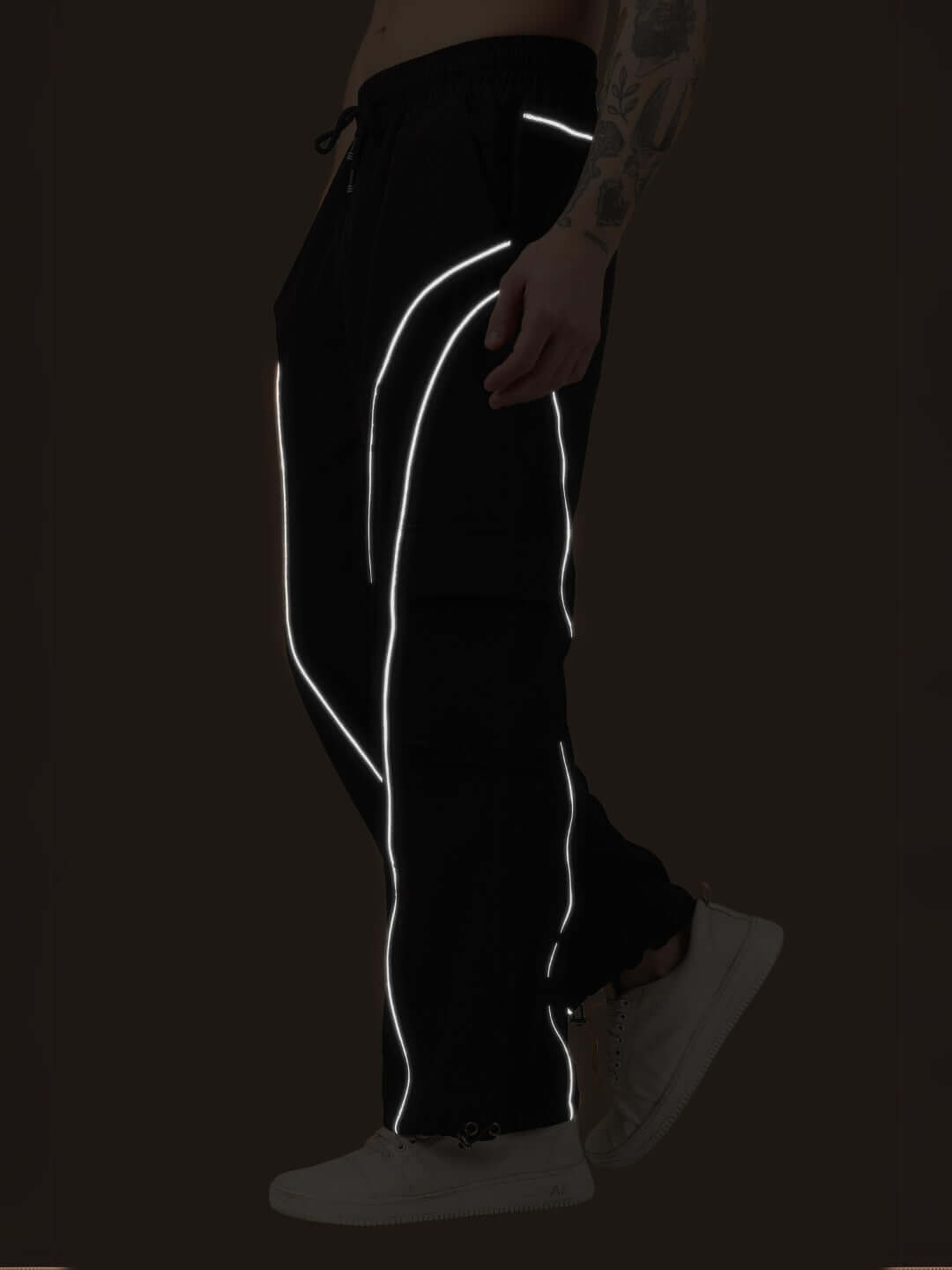 Side view of black RAY REFLECTOR PARACHUTE CARGO PANTS showcasing reflective details in a stylish design for versatile wear.