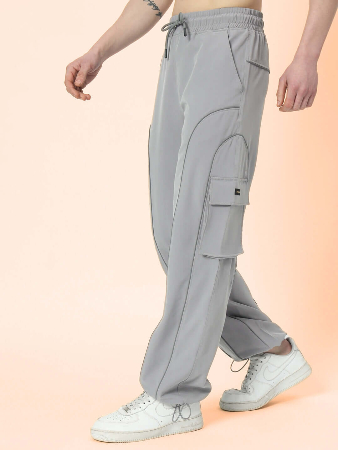 Model wearing grey Ray Reflector Parachute Cargo Pants with custom fit option, featuring side pockets, perfect for casual and stylish wear.