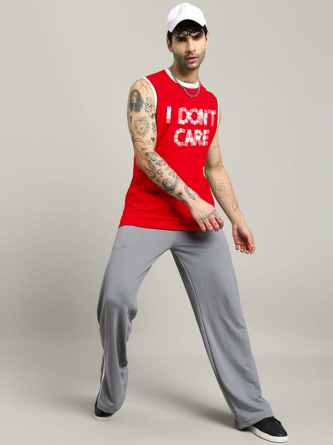 Man wearing a red 'I DON'T CARE' gym t-shirt with gray pants, showcasing casual fashion style.