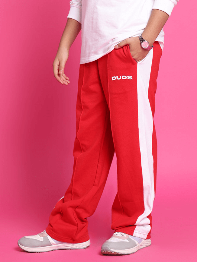 Child wearing red unisex stitch jogger pants by DUDS, featuring white stripe design, styled for both boys and girls.