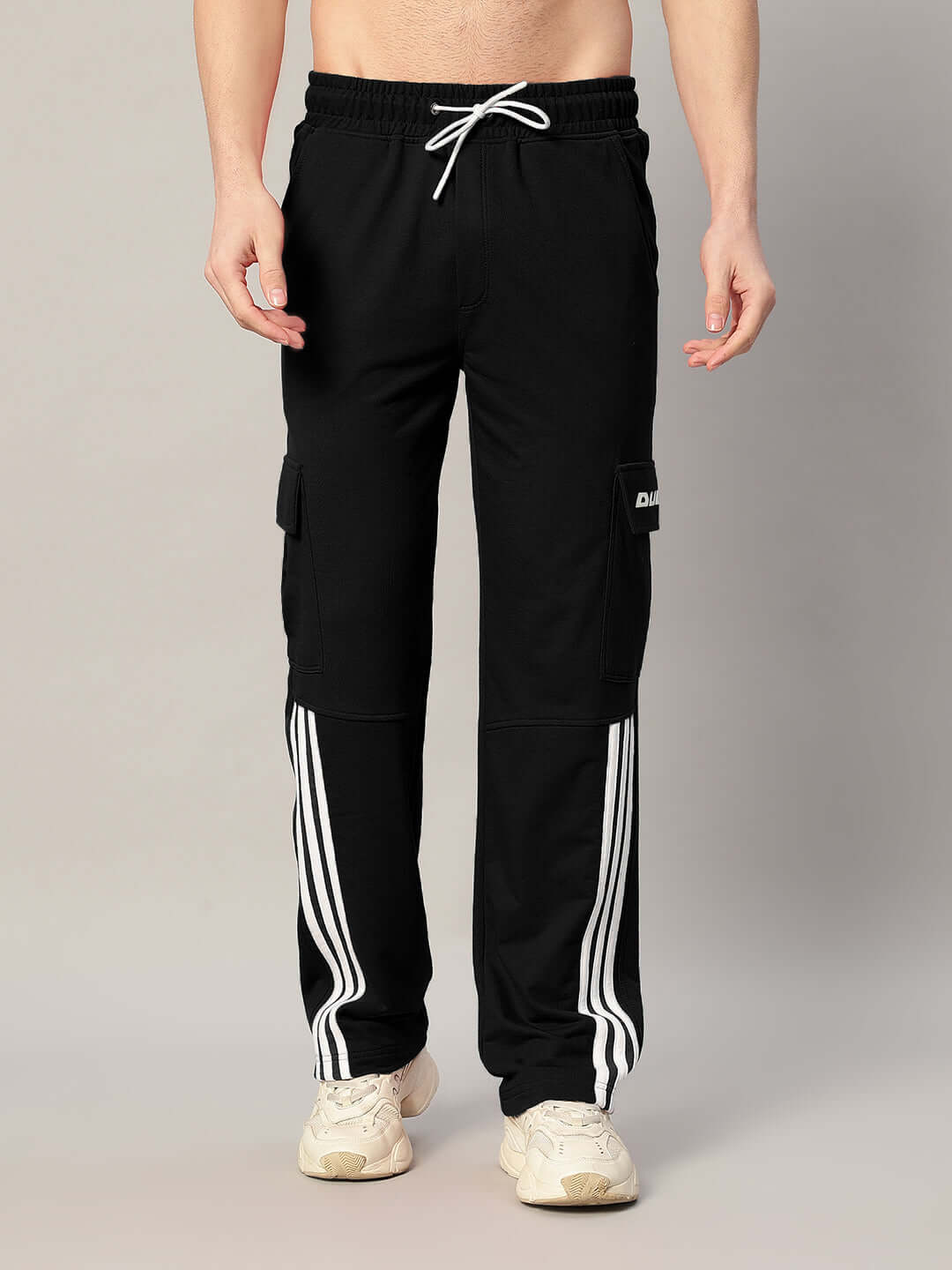 Model wearing REDROIT black joggers with relaxed fit and 5 pockets, featuring sporty white stripes, crafted by DUDS tailors.