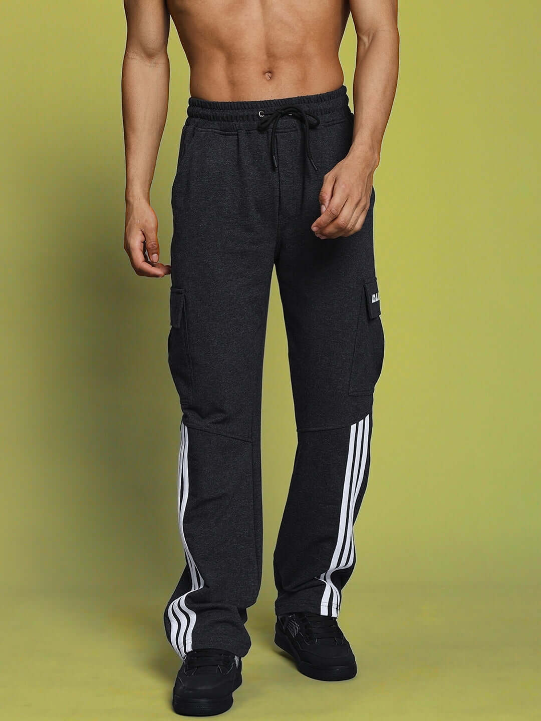 Person wearing REDROIT 5 pocket relaxed fit joggers in dark grey with side stripes, displayed against a yellow background.