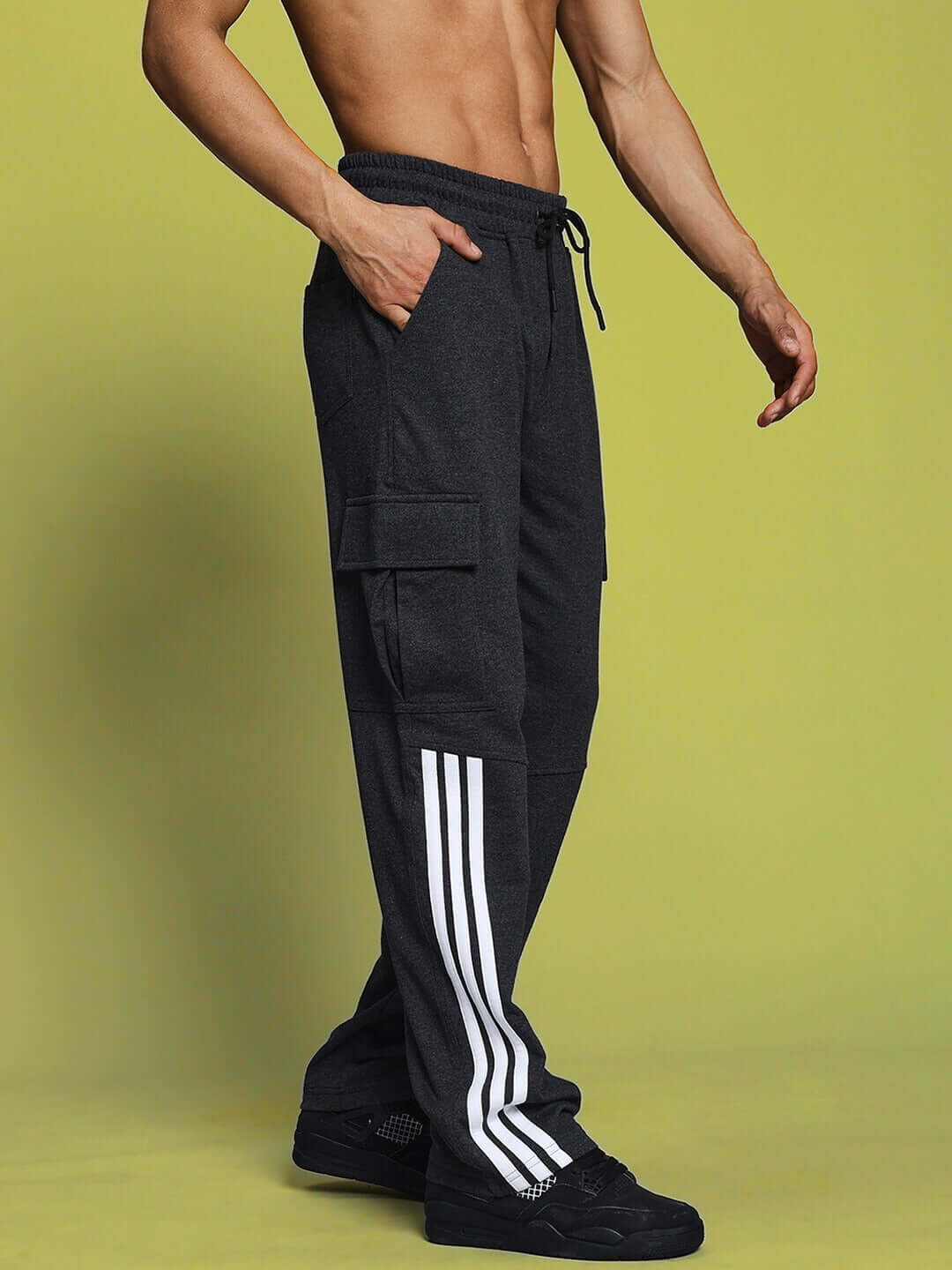 Model wearing Redroit dark grey relaxed fit joggers with five pockets and white stripe detail, showing custom fit and tailored craftsmanship.
