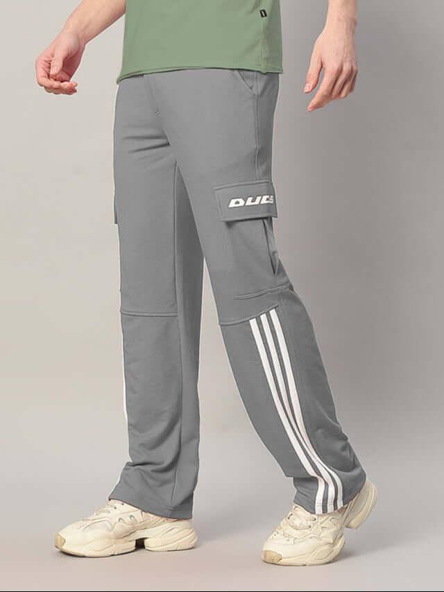 Man wearing grey REDROIT 5 Pocket Relaxed Fit Joggers with white stripes, featuring DUDS branding, paired with white sneakers and green shirt.