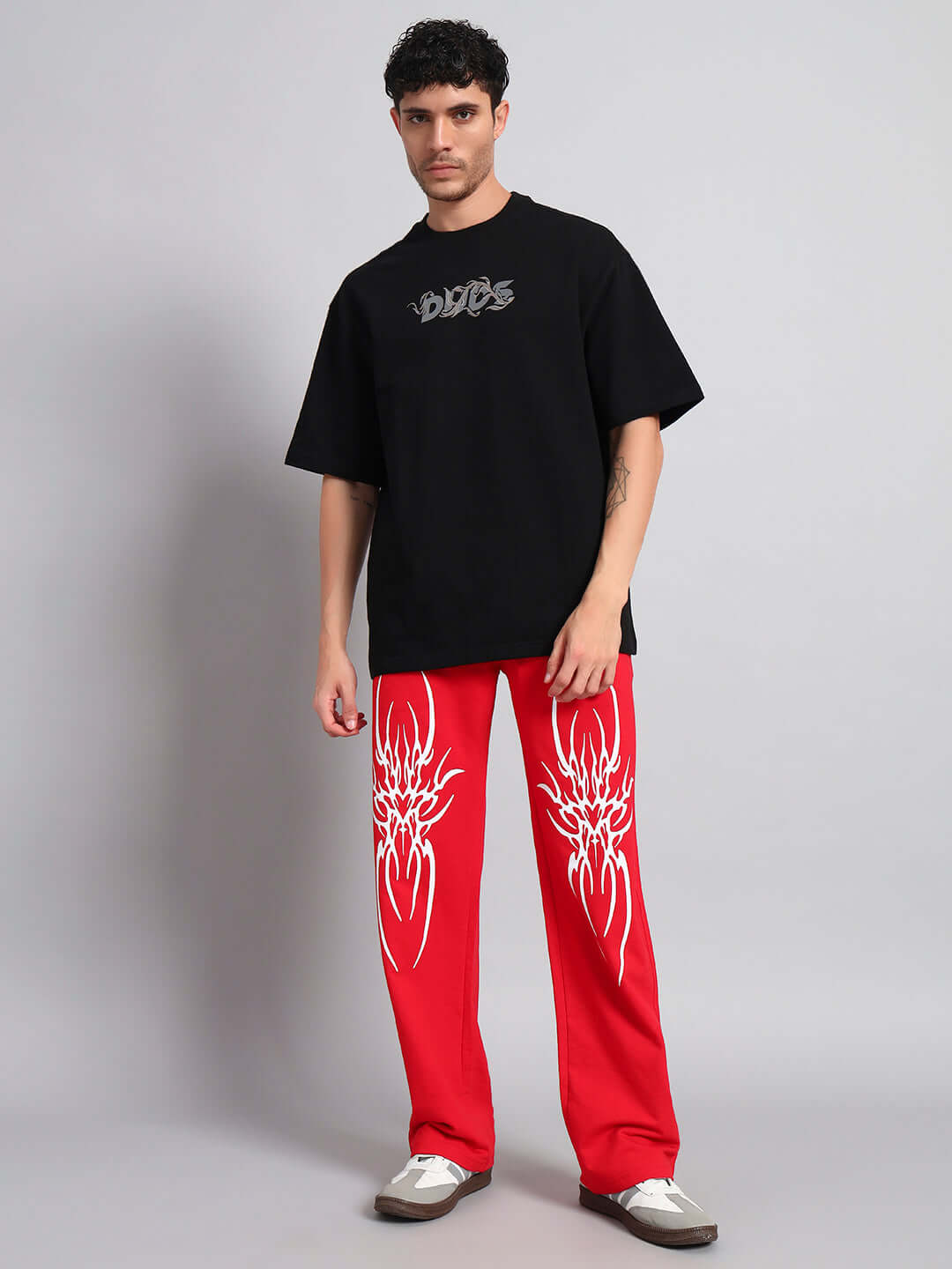 Man wearing REDX BRANCHING COTTON JOGGER RED MEN with graphic design, paired with black t-shirt and white sneakers.