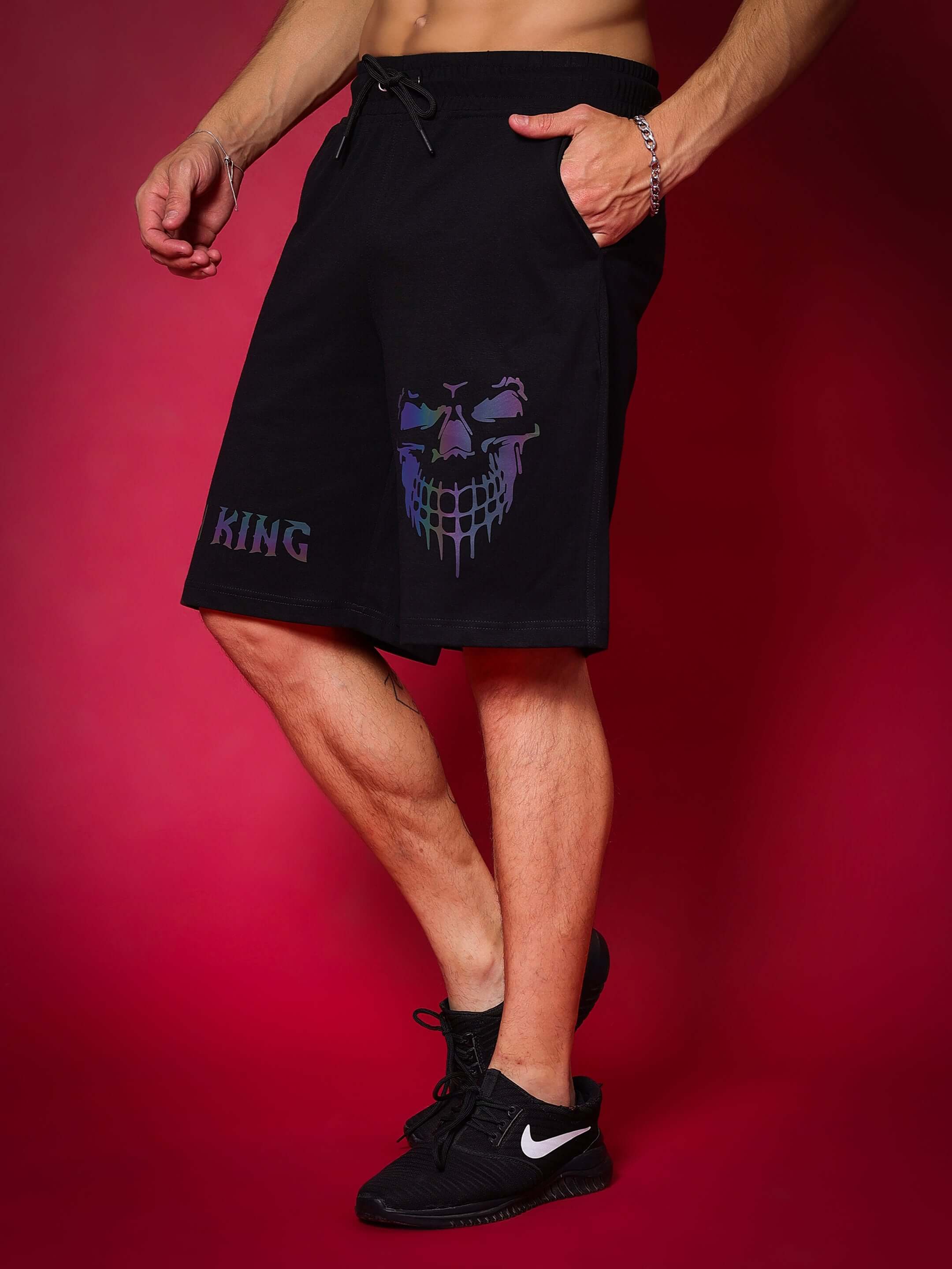 Man wearing black REFLECTOR JYM KING shorts featuring custom fit option against a red background.