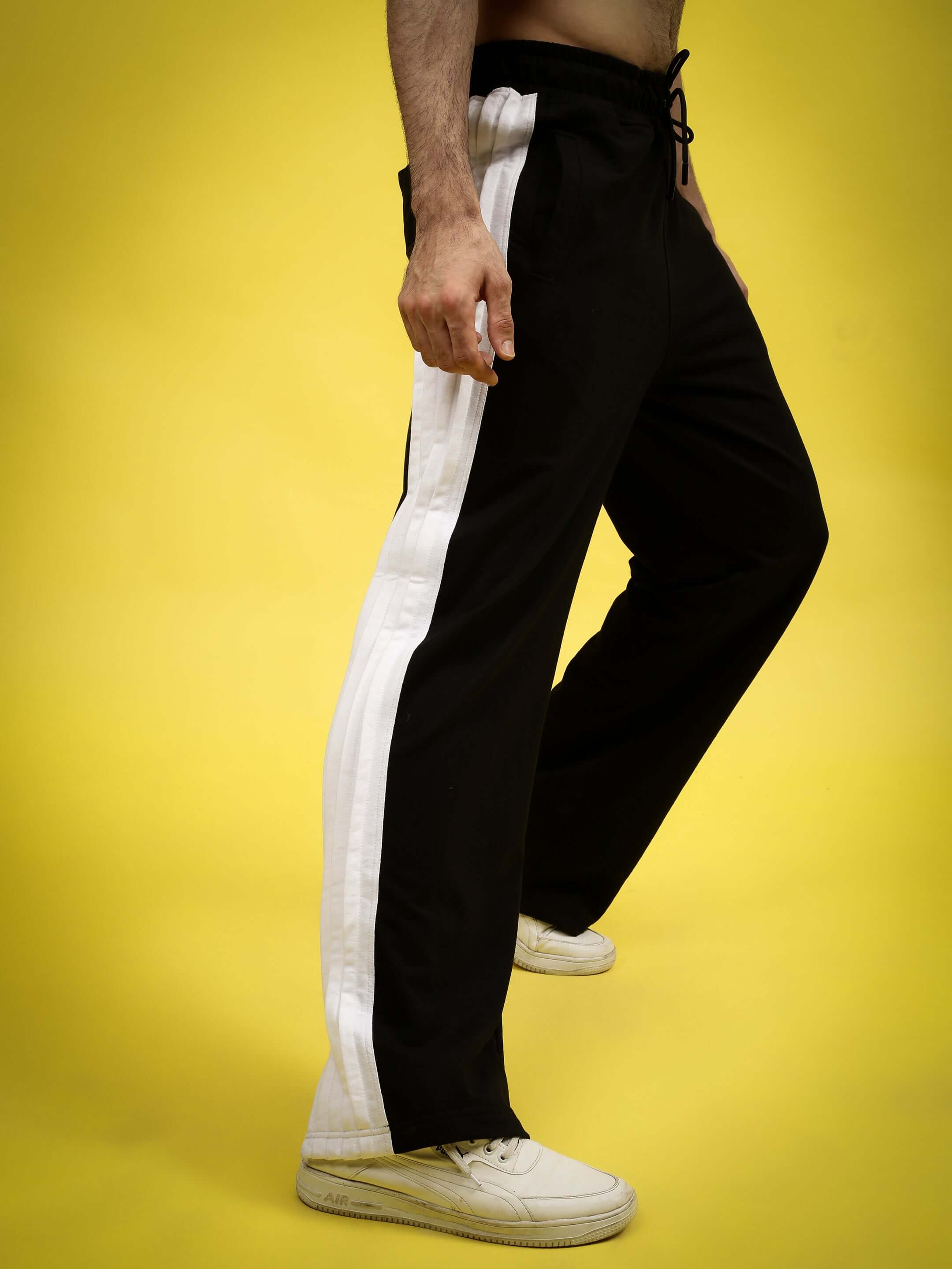 Model wearing REGAL BAGGY JOGGERS in black and white, made-to-order from DUDS, shown on a bright yellow background.