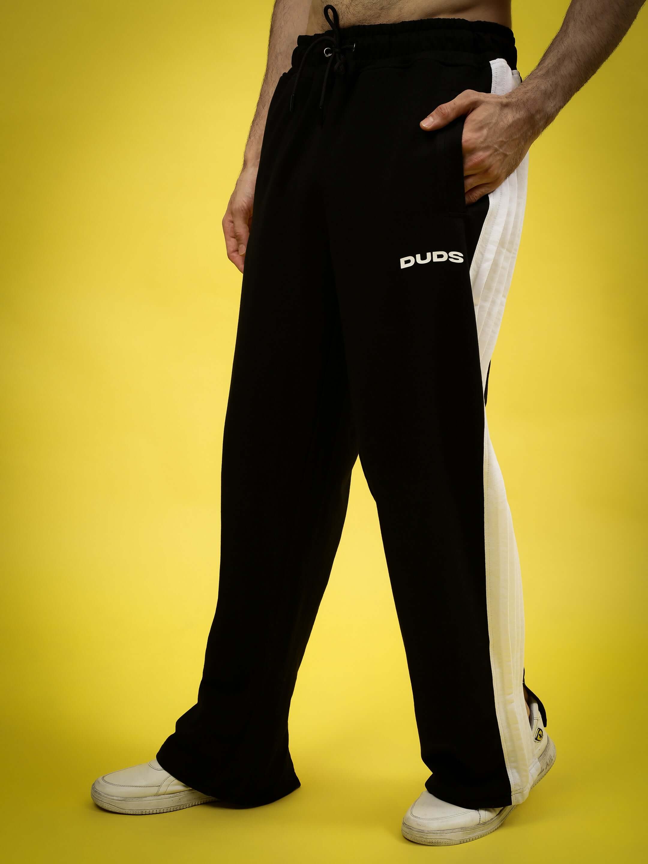 Model wearing REGAL BAGGY JOGGERS in black and white by DUDS, showcasing relaxed fit and side pockets, perfect for comfort and style.