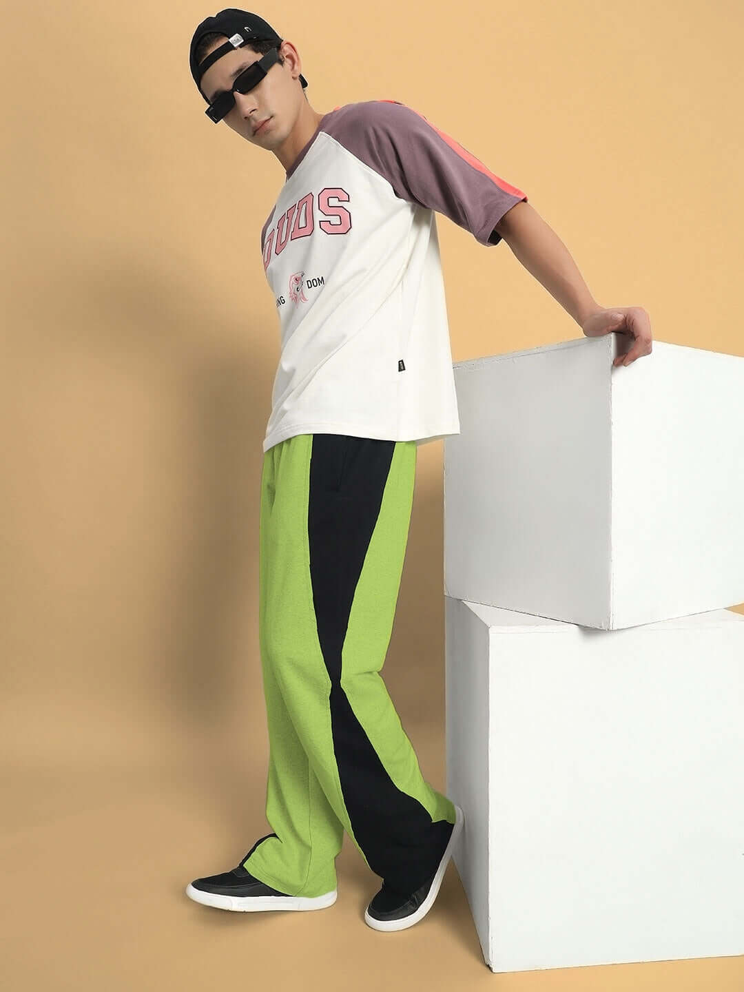 Model wearing REVIVE Side Contrast Joggers in neon green, paired with a casual top and black sunglasses, posing stylishly against a minimalist backdrop.