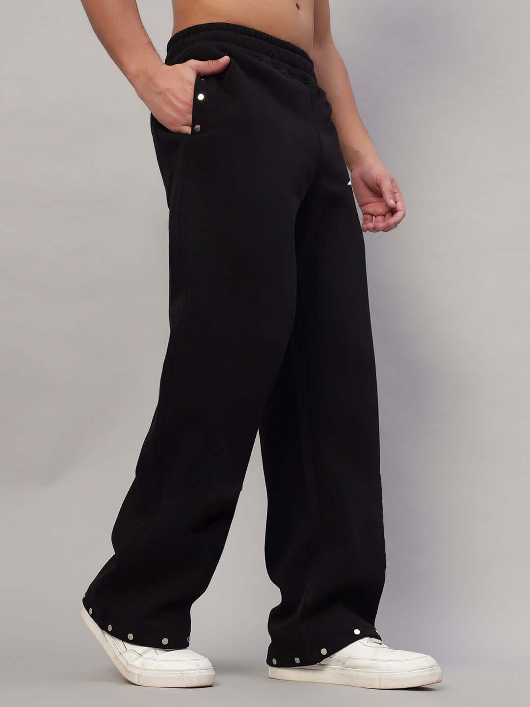 Black rigid cotton fleece jogger with side pockets and button details, styled with white sneakers for a casual look.
