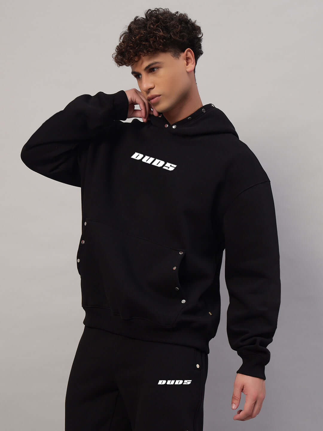 Model wearing WEARDUDS RIGID FLEECE HOODIE BLACK with hands in pockets, highlighting comfy and stylish design.