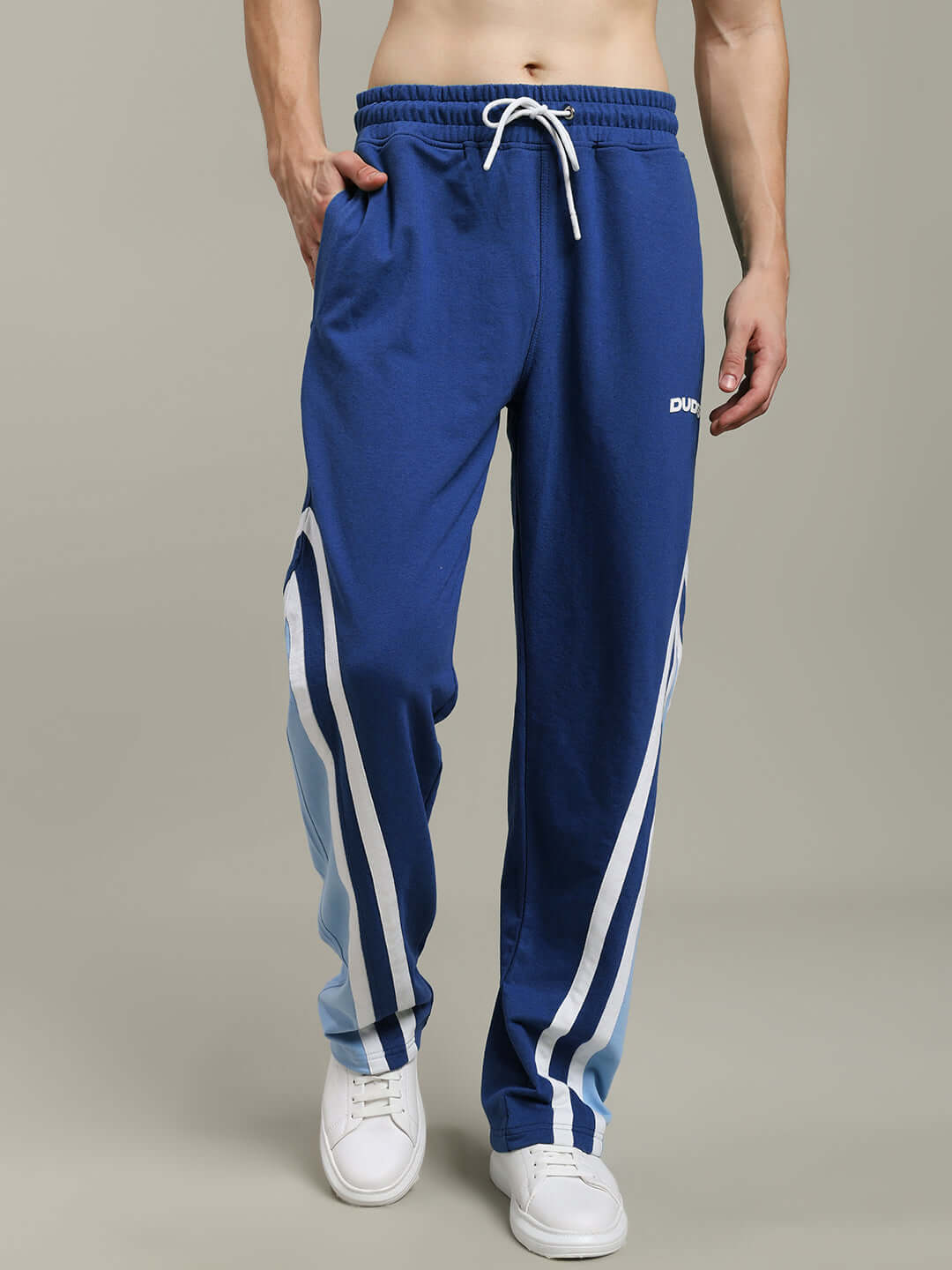 Model wearing blue RIO ONE relaxed fit joggers by DUDS, featuring white side stripes. Custom fit option available.