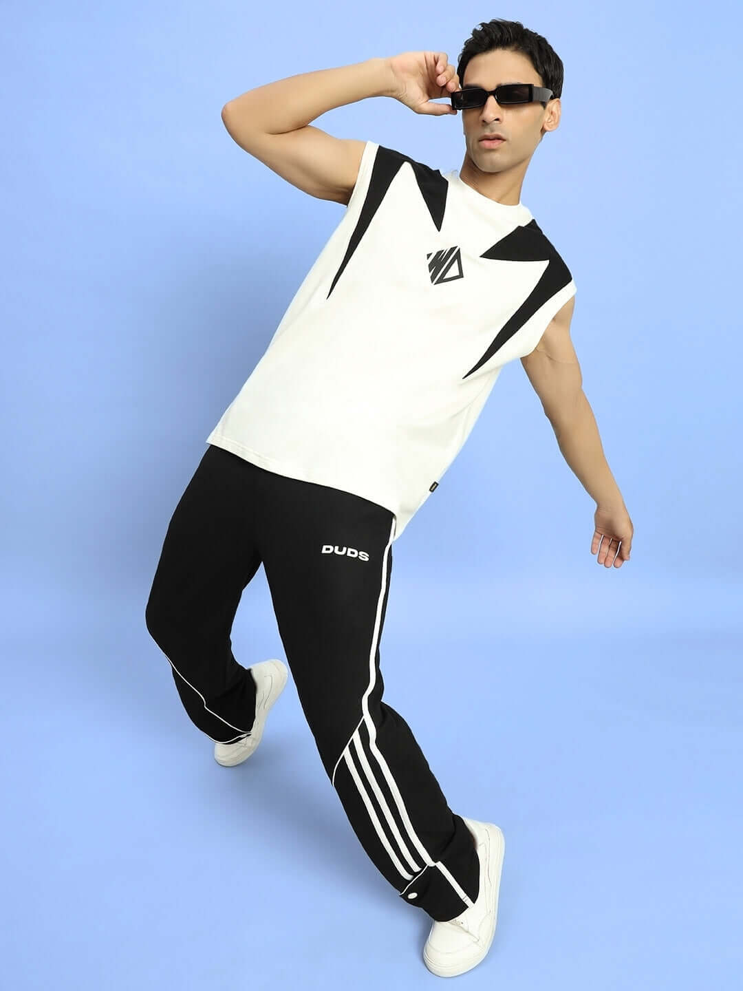 Model wearing DUDS Ripple Contrast Joggers in black, striking a pose against a blue background, showcasing casual sporty style.