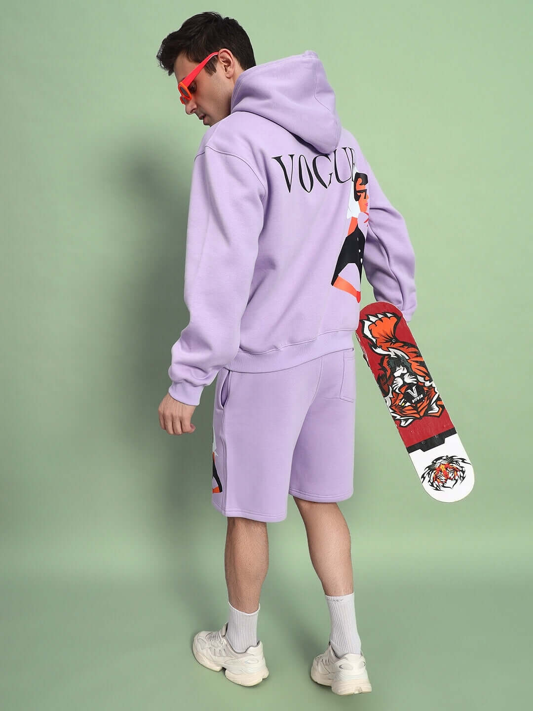 Model wearing WEARDUDS RITZY FLEECE CO-ORD LILAC with hoodie and shorts holding skateboard.