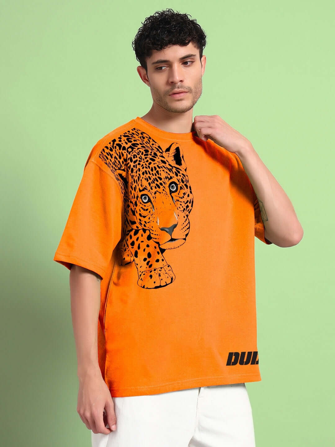 Man wearing an orange Roberto leopard printed T-shirt made from premium heavy gauge fabric, featuring a distinctive leopard design.