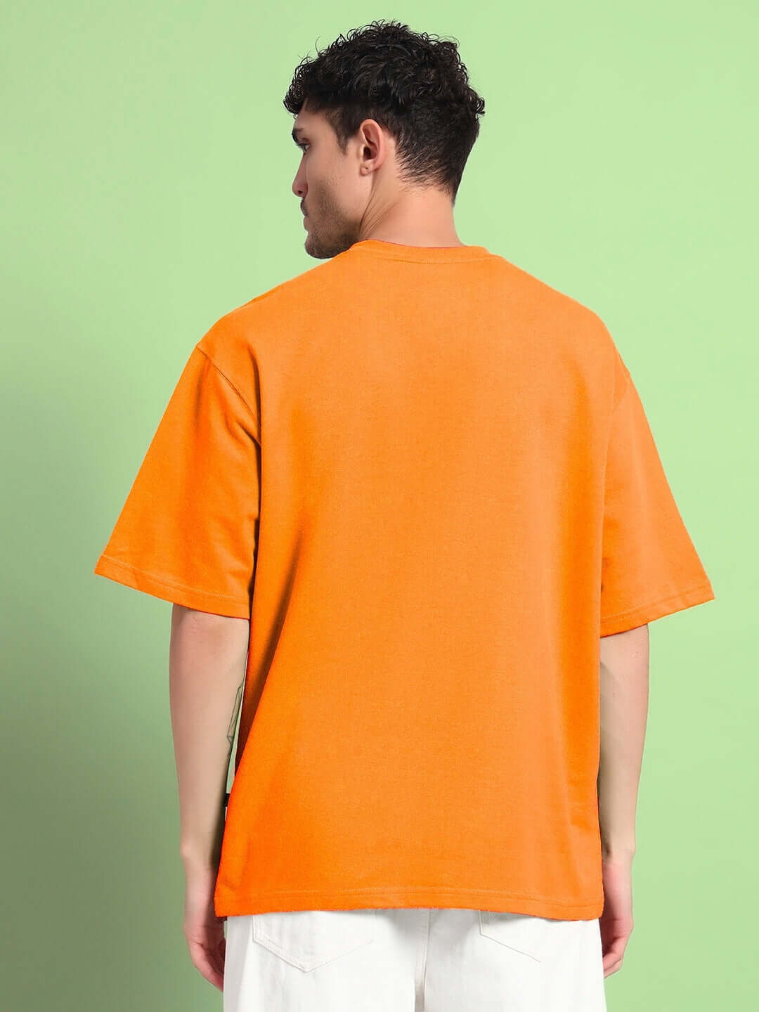 Back view of ROBERTO LEOPARD PRINTED T-SHIRT ORANGE worn by a model, showcasing vibrant design on a green background.