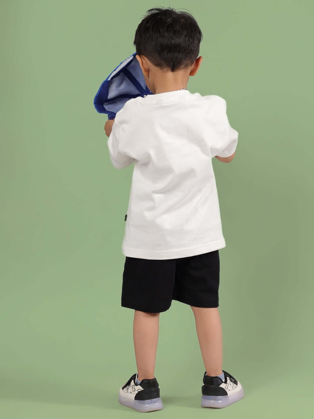 Child wearing ROBIN CO-ORD FOR BOYS & GIRLS OFF WHITE-BLACK standing against a green background.