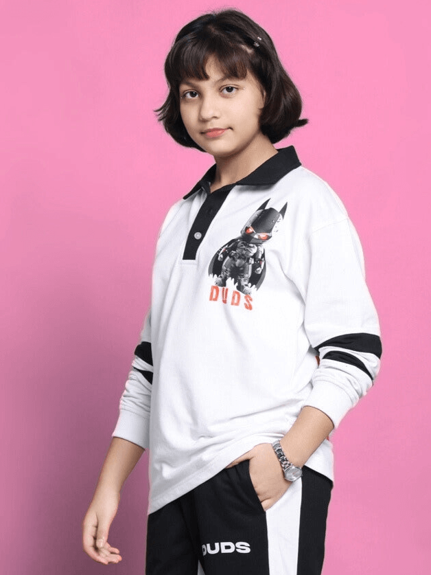 Child wearing a white Robin oversized sweatshirt with graphic design, against a pink background.