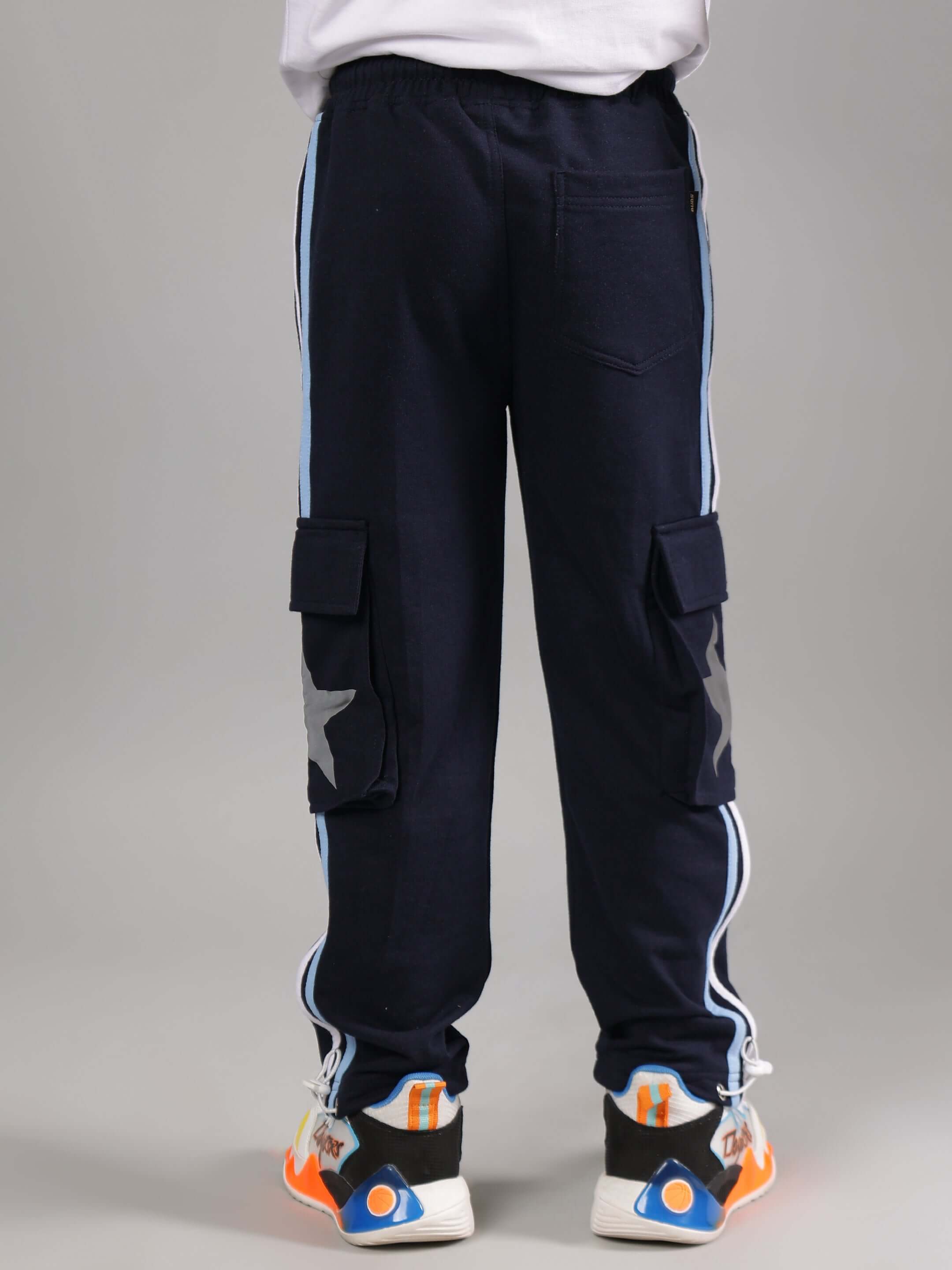 Child wearing navy pants from ROBO MINIONS CO-ORD FOR BOYS GIRLS WHITE NAVY, featuring side stripes, star patches, and bright sneakers.