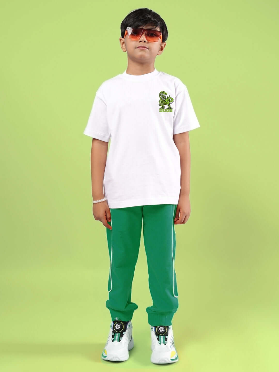 Child wearing ROBO REX CO-ORD FOR BOYS & GIRLS WHITE-GREEN outfit with white shirt and green pants on a green background.
