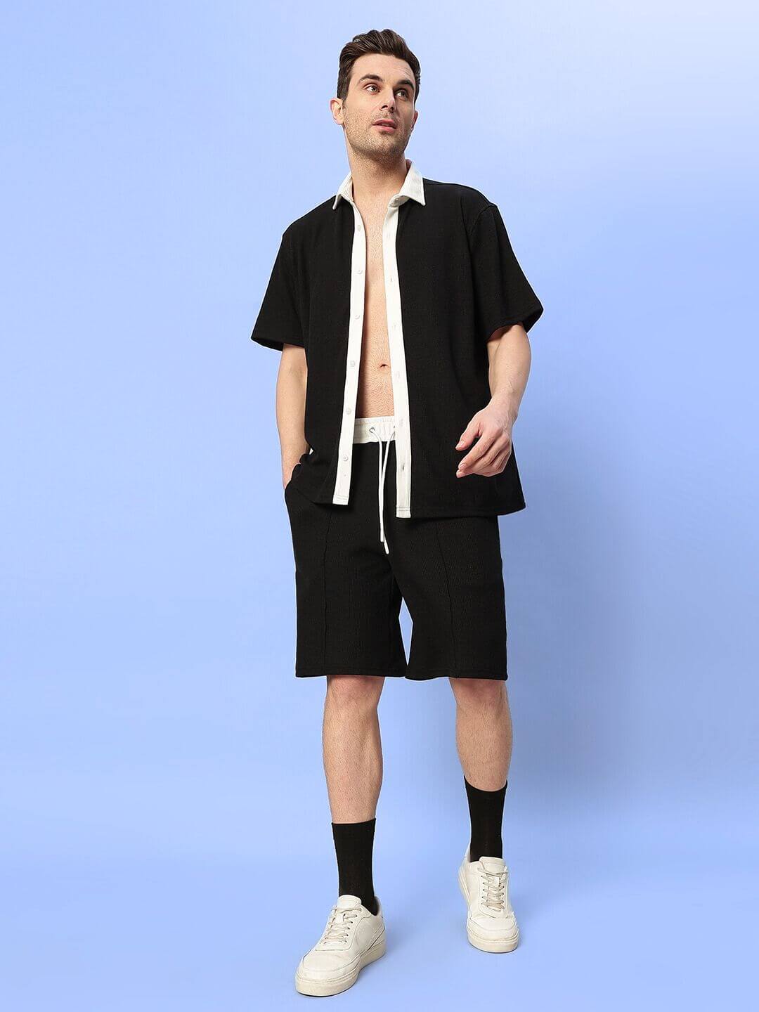Man wearing Robson Co-Ord Set in black, waffle fabric, 100% cotton, relaxed fit, half sleeves, against light blue background.