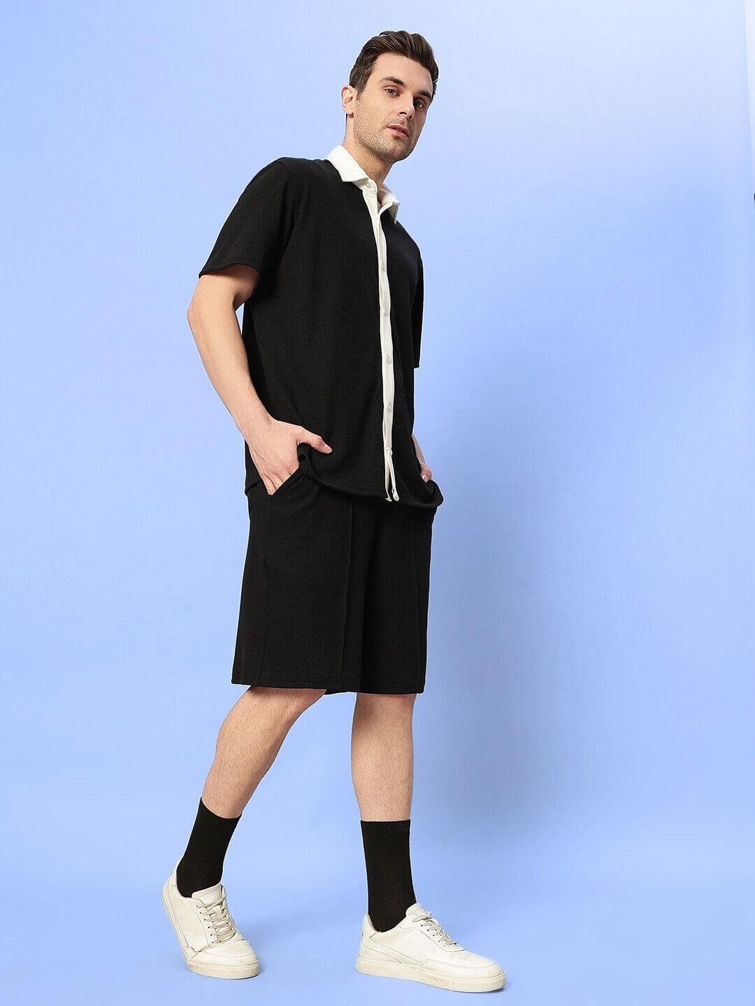 Model wearing Robson Co-Ord Set in black waffle fabric, featuring half sleeves and relaxed fit, standing against light blue background.