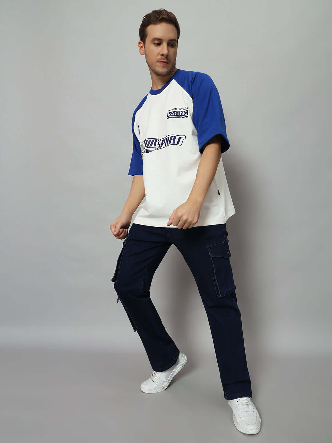 Man wearing navy denim cargo jeans and blue-white t-shirt, showcasing casual fashion style.