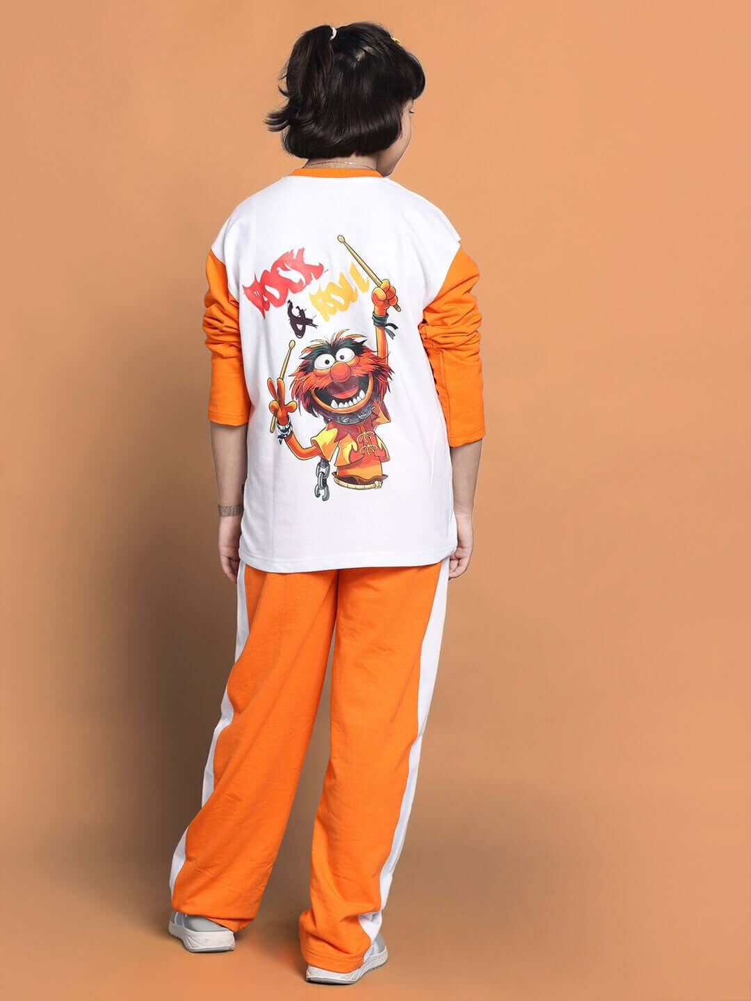 Child wearing unisex white and orange rock & roll oversized co-ord set with relaxed fit joggers, featuring cartoon graphic on the back.