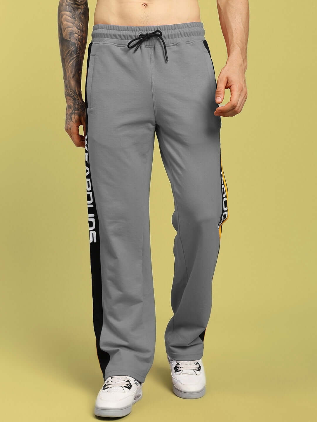 Man wearing grey ROGER relaxed-fit joggers with drawstring, showcasing side stripe detail, available for custom fit from DUDS.