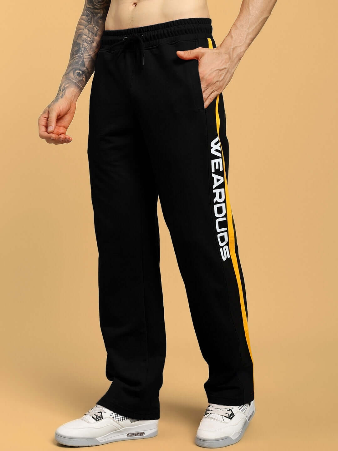 Model wearing black ROGER relaxed-fit joggers with yellow stripe, made to order by DUDS Tailors.