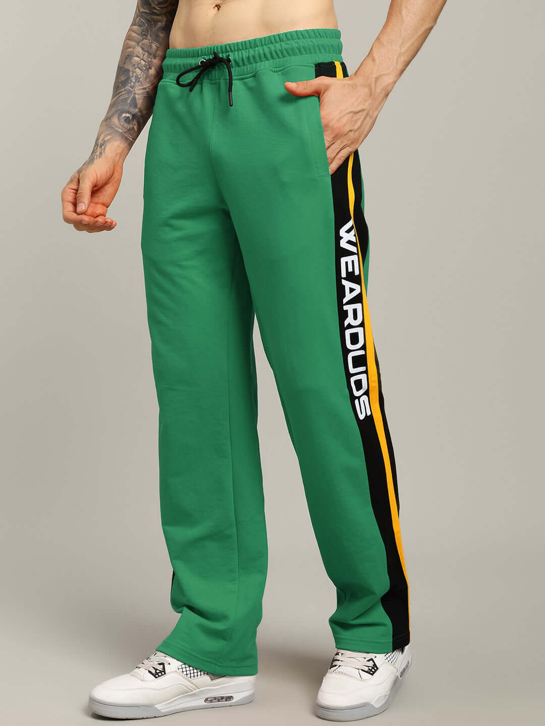Green relaxed-fit joggers with side stripe and 'WEAR DUDS' logo, shown on a model, ideal for comfort and style.