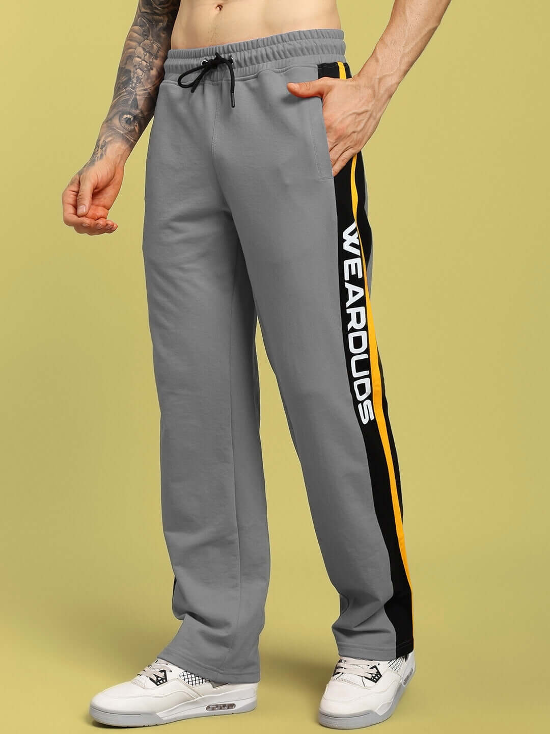 Model wearing ROGER Relaxed-Fit Joggers in grey, featuring side stripes and WEAR DUDS branding, tailored for comfort and style.