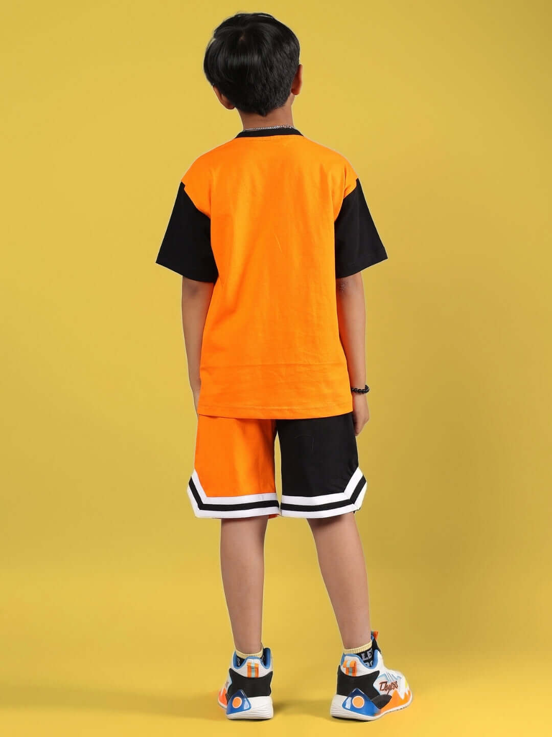 Child wearing ROGUE RIDER CO-ORD FOR BOYS & GIRLS ORANGE BLACK, showcasing back design against yellow background.
