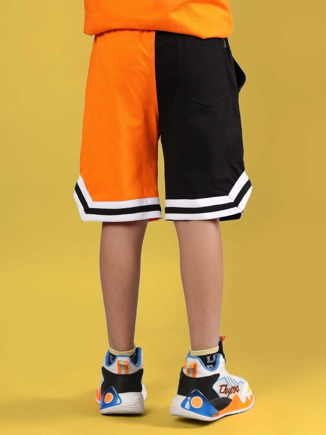 Back view of ROGUE RIDER black-orange shorts for kids, showcasing vibrant design and dual color pattern. Custom fit available.
