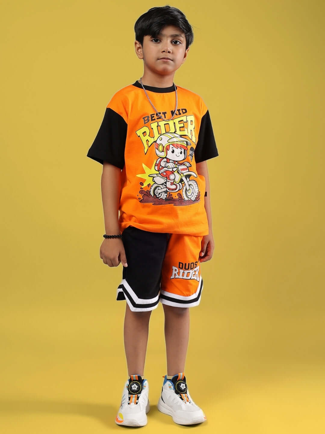 Child wearing ROGUE RIDER Co-Ord set in orange and black, featuring a motorcycle print, designed for both boys and girls by DUDS.