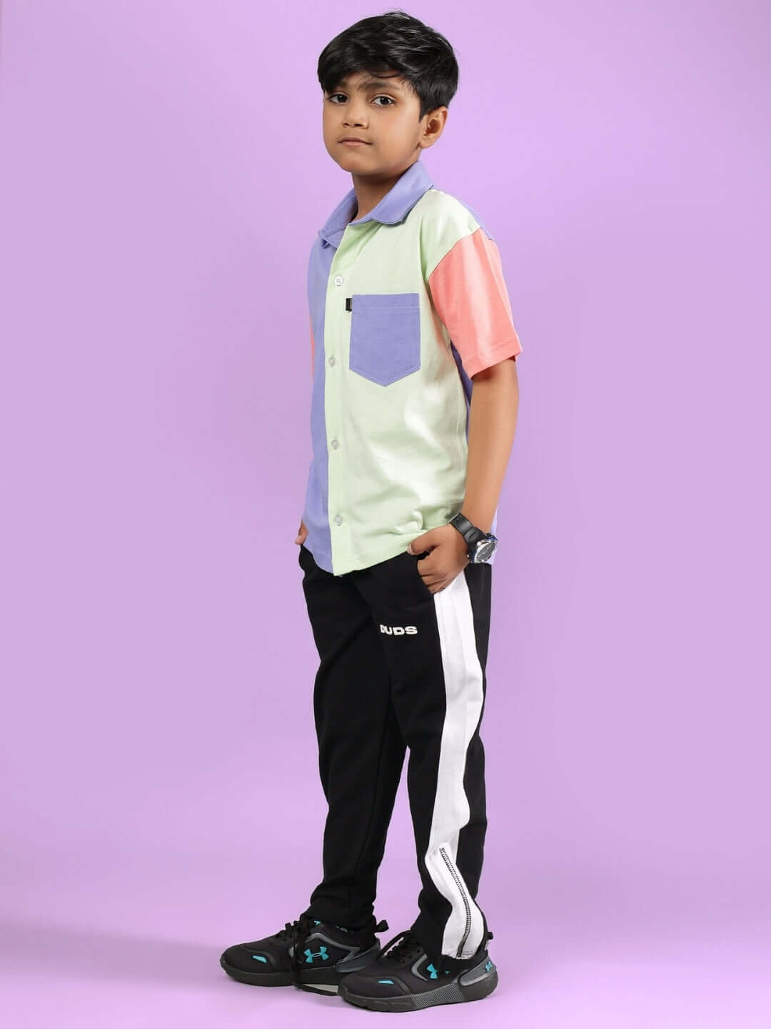 Child wearing ROMAN CO-ORD FOR BOYS & GIRLS MULTI-BLACK with colorful shirt and black pants, posing on a purple background.