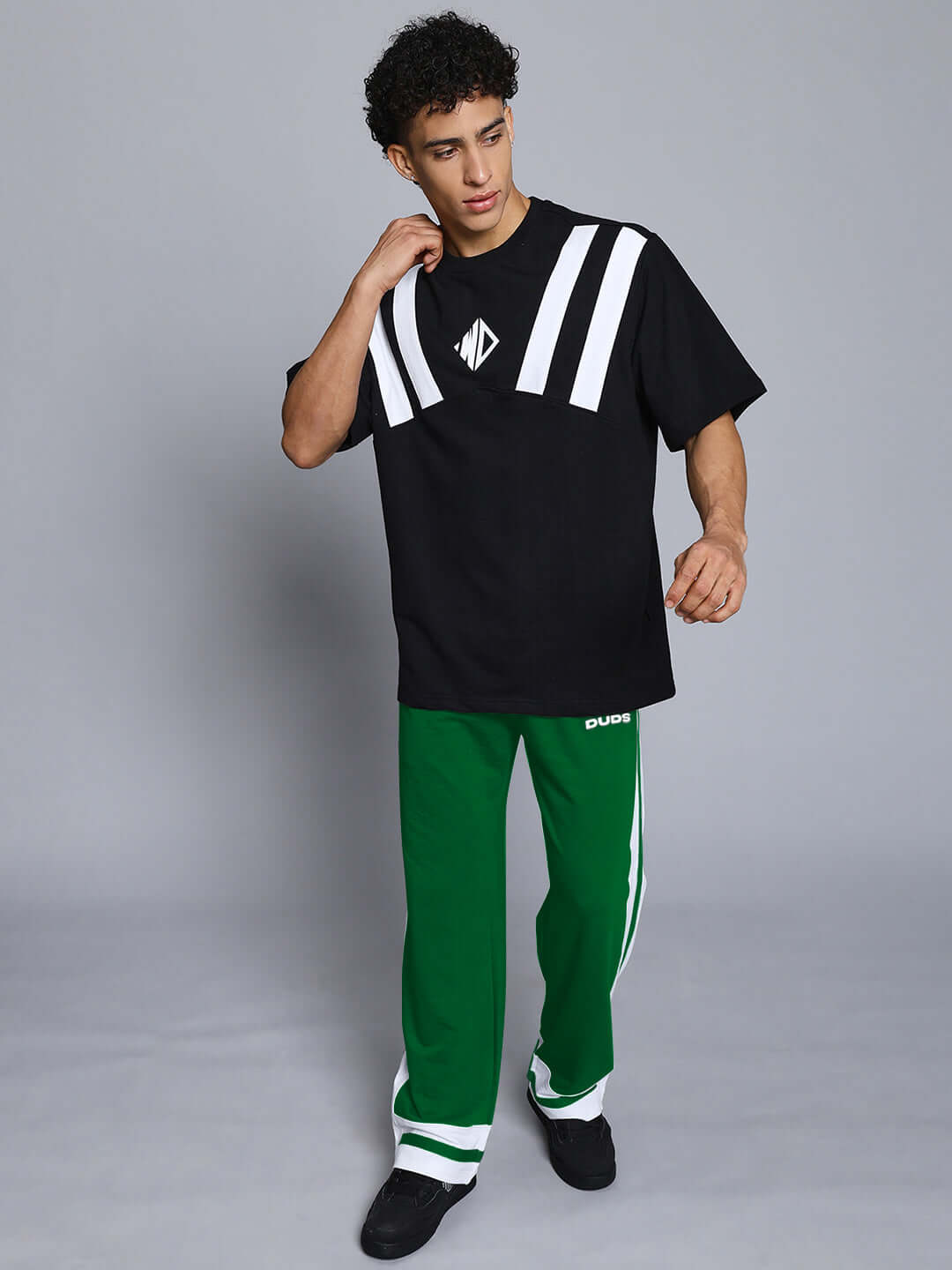 Model wearing green-white Ronny side stripe joggers paired with a black and white shirt, showcasing a casual look. Made by DUDS.