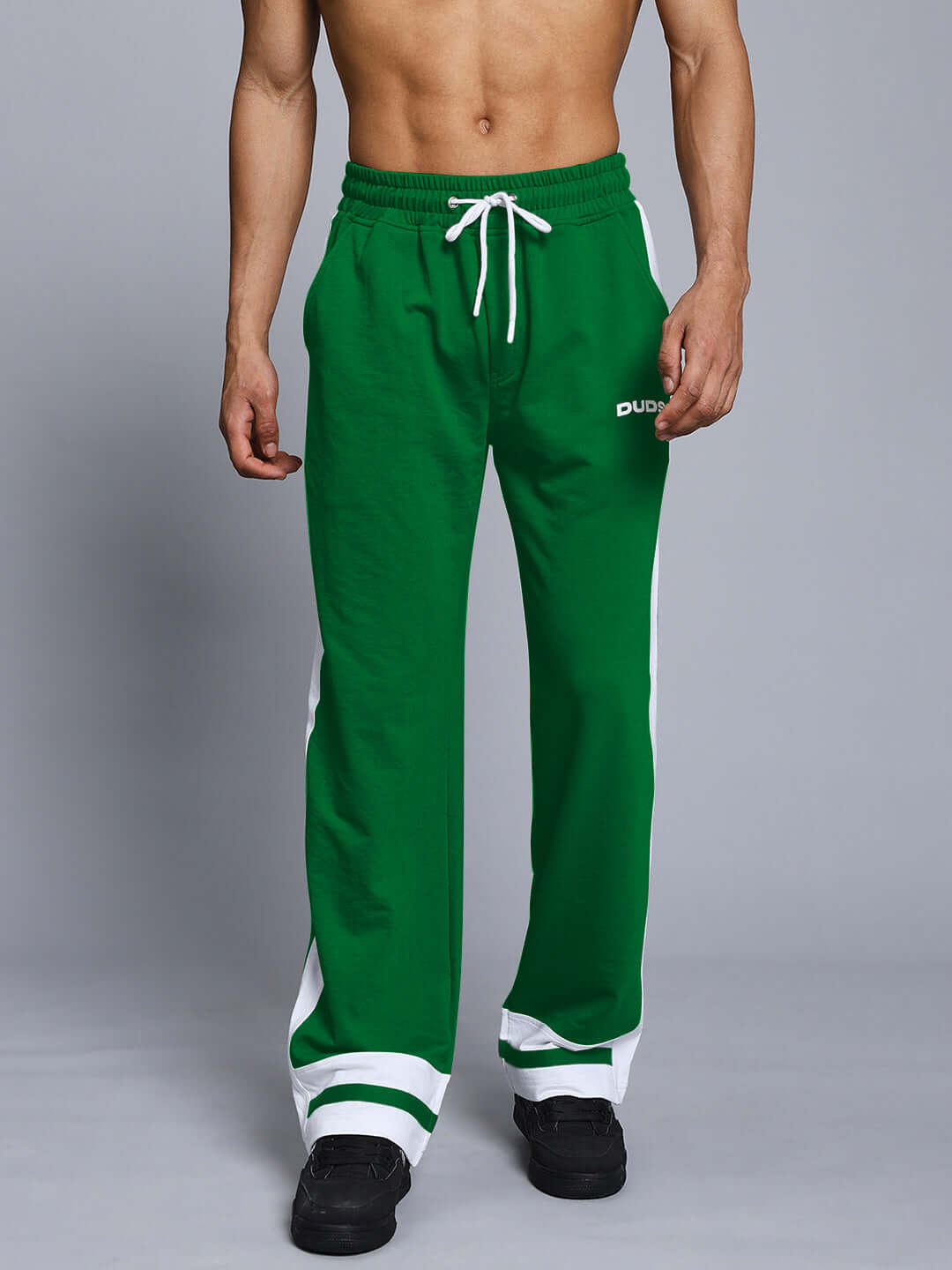 Model wearing green joggers with white side stripes, featuring adjustable waist and logo detail from DUDS.