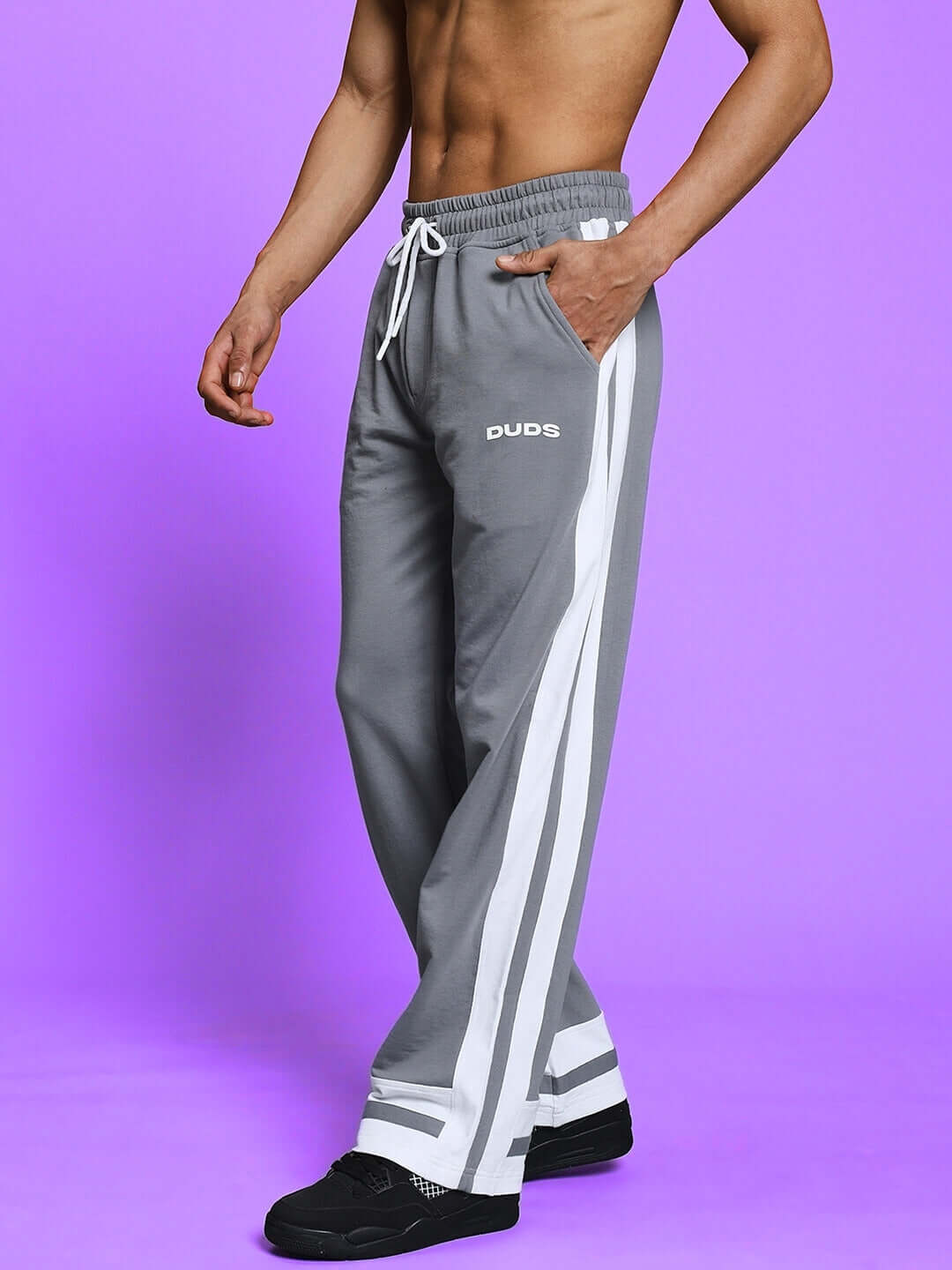 Man wearing grey joggers with white side stripes from DUDS, featuring adjustable drawstring and custom fit options.
