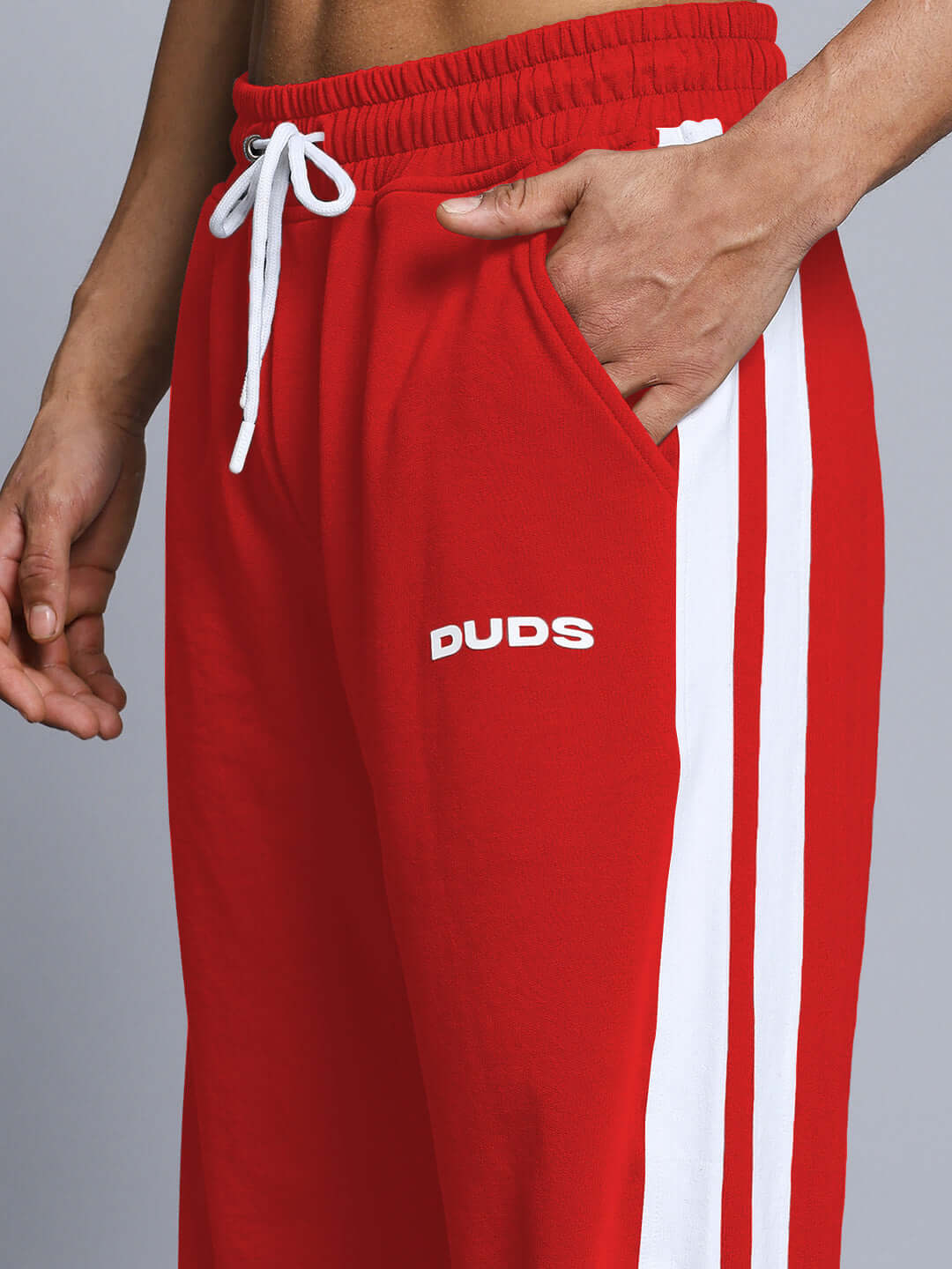 Red jogger pants with white side stripe and drawstring, featuring 'DUDS' branding, showcasing a stylish and comfortable fit.