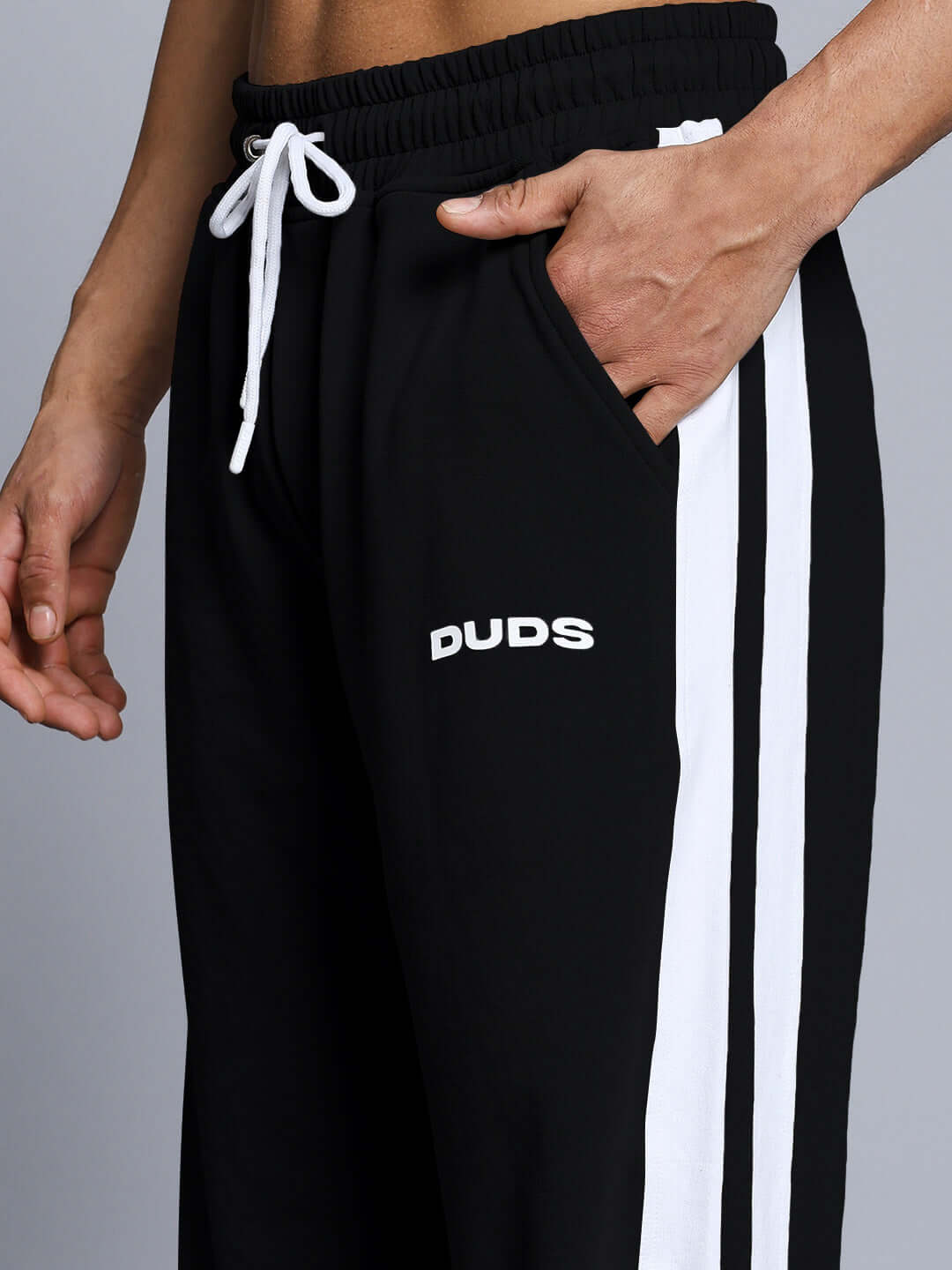 Black joggers with white side stripes and 'DUDS' logo, features comfortable elastic waistband and drawstring, customizable fit available.