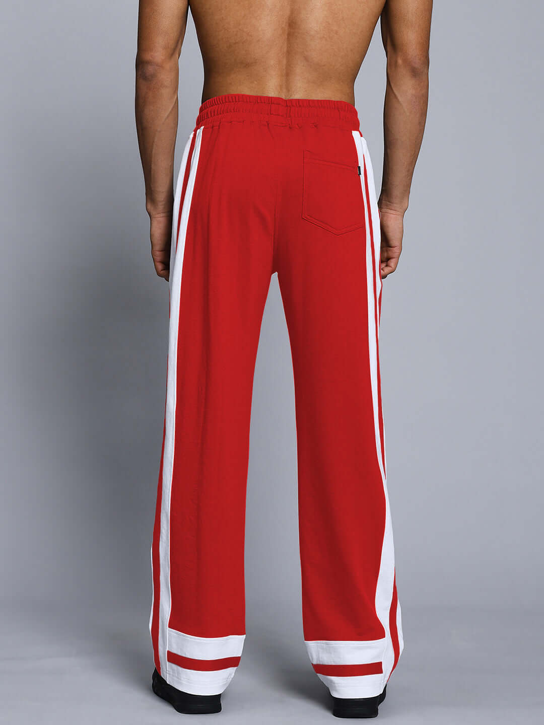 Red Ronny joggers with white side stripes, back view, showcasing custom fit tailoring by DUDS. Made to order, men's athletic wear.