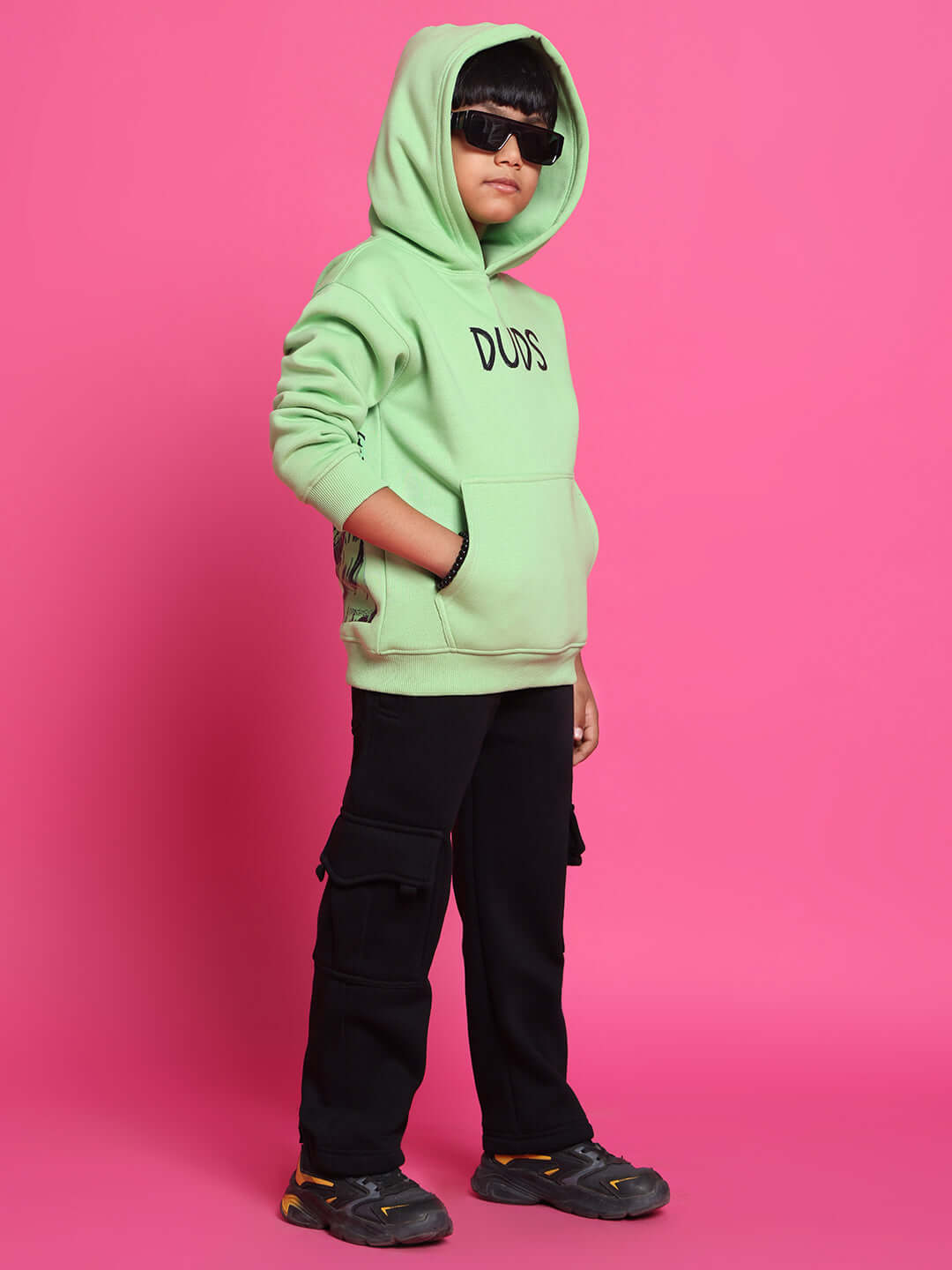 Child wearing ROOAR CO-ORD FOR BOYS GIRLS NEON GREEN with black pants and sunglasses against pink background.
