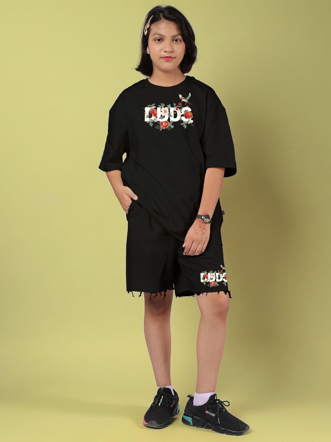 Child wearing ROSE CHARM CO-ORD FOR BOYS AND GIRLS BLACK outfit, standing against yellow background.