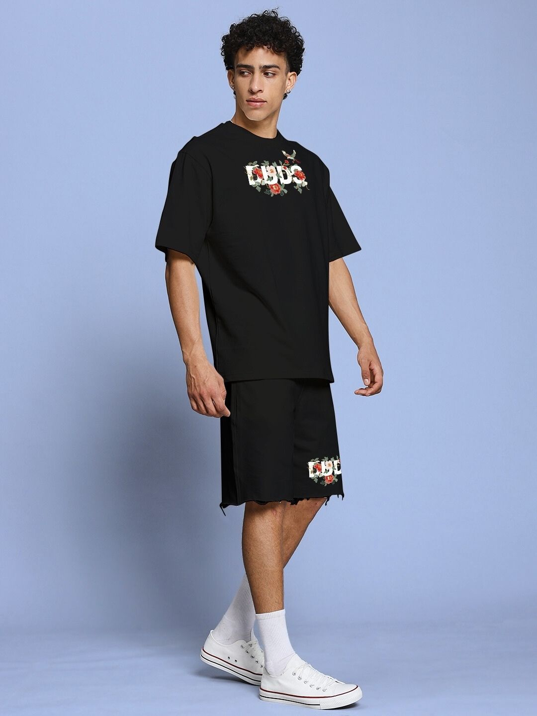Model wearing ROSE CHARM RELAXED FIT CO-ORD SET BLACK, featuring floral accents on a black background, showcasing a casual summer style.