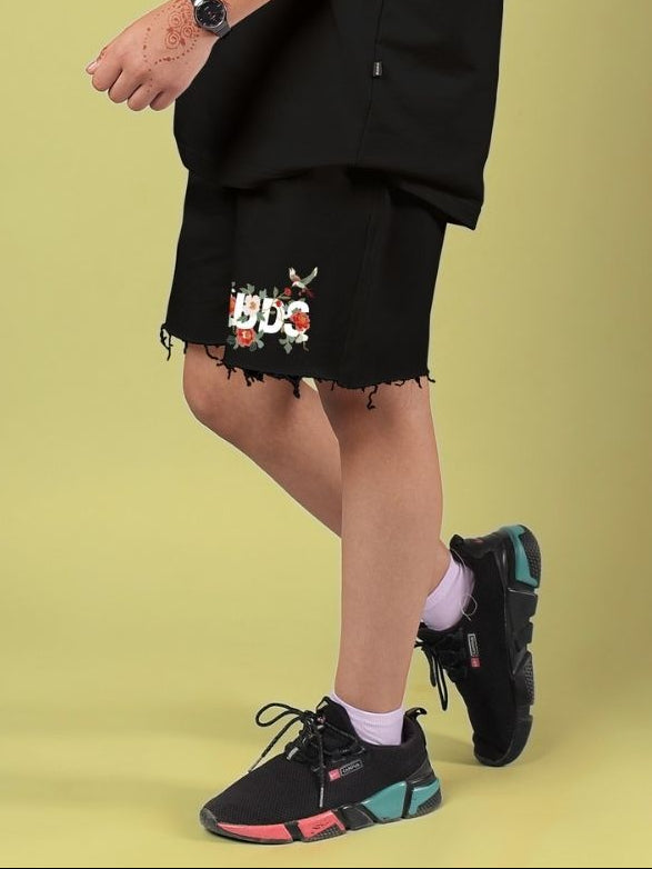 Child wearing ROSE CHARM SHORTS FOR BOYS AND GIRLS BLACK with sneakers