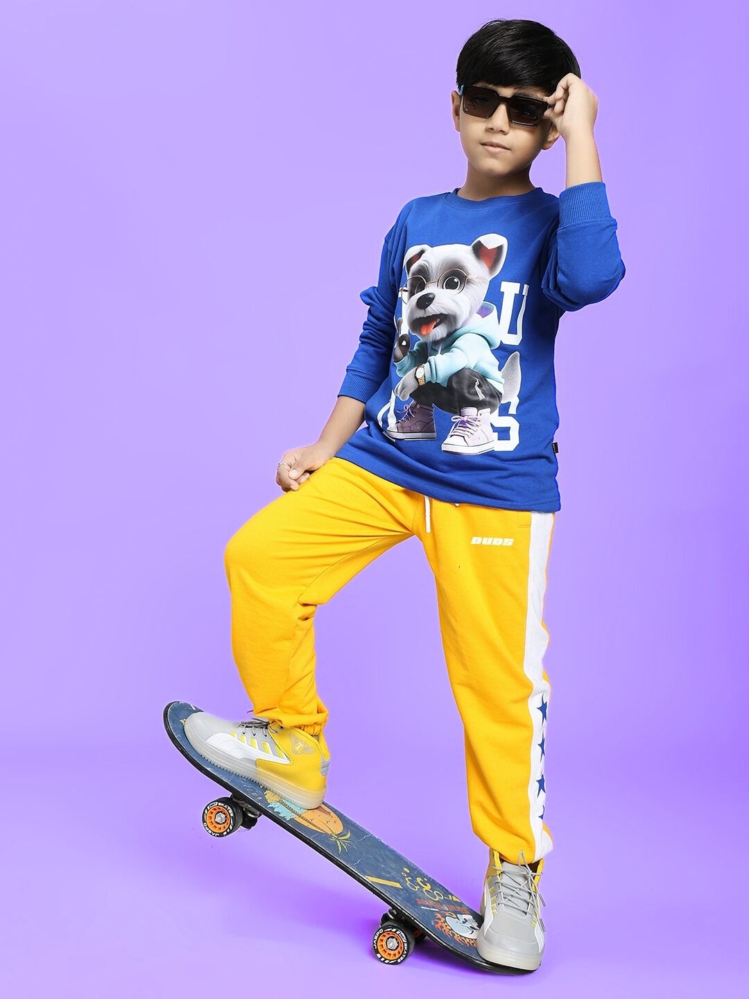 Boy wearing ROX PRIMER JOGGER FOR BOYS AND GIRLS YELLOW WHITE with skateboard, showcasing eye-catching design in a playful pose.