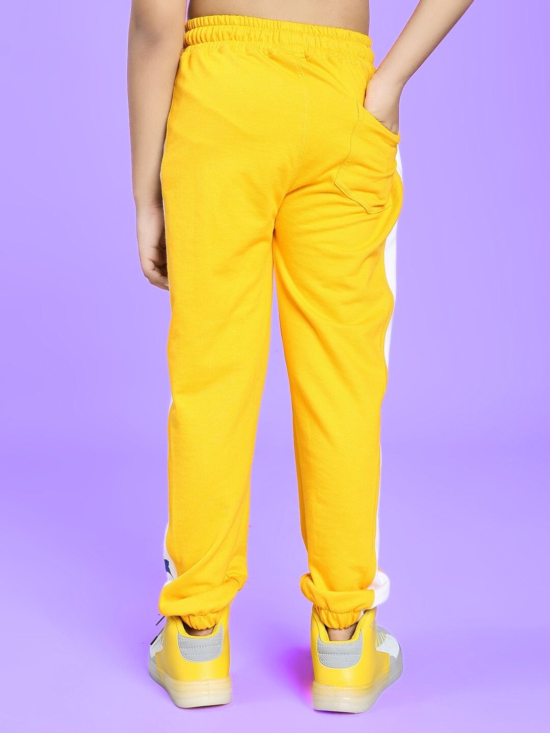 Child wearing ROX PRIMER JOGGER FOR BOYS AND GIRLS YELLOW WHITE in a playful stance.